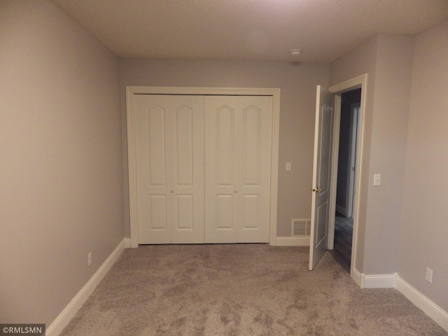 unfurnished bedroom featuring carpet floors, a closet, visible vents, and baseboards