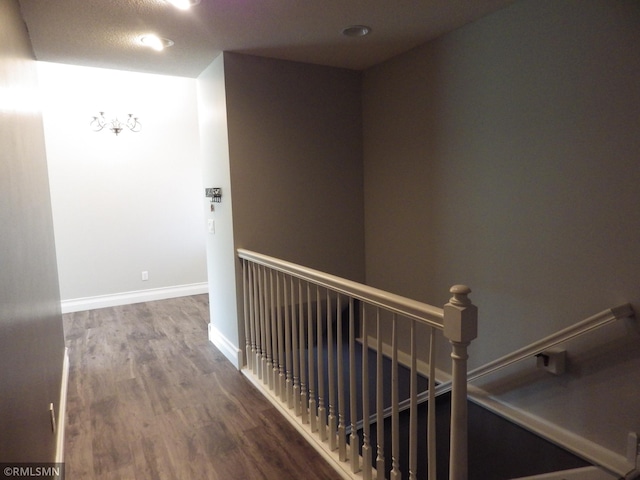 hall featuring an upstairs landing, baseboards, and wood finished floors