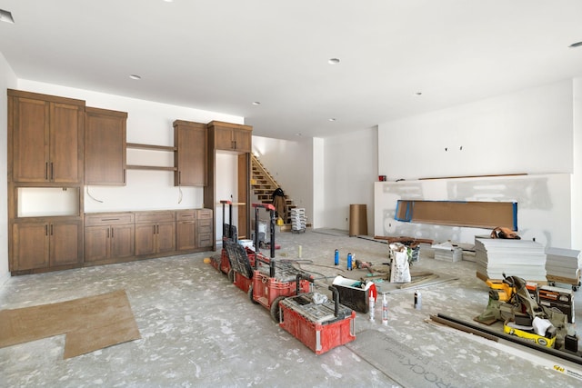 kitchen featuring open floor plan, open shelves, brown cabinets, and unfinished concrete floors