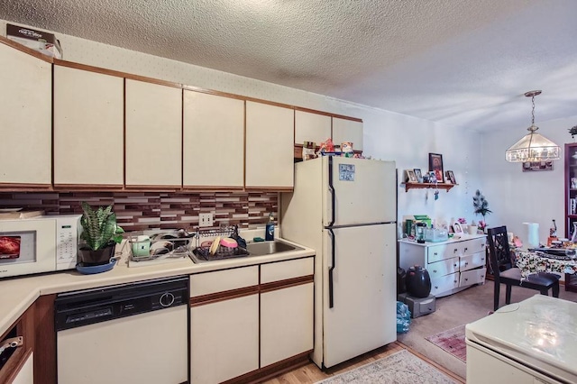 kitchen featuring backsplash, cream cabinetry, a textured ceiling, white appliances, and hanging light fixtures