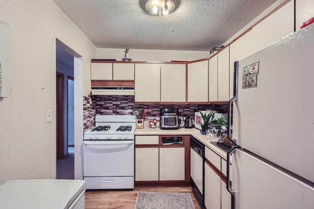 kitchen with a textured ceiling, white appliances, light hardwood / wood-style floors, and tasteful backsplash