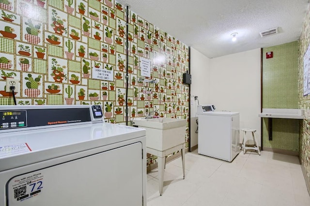 washroom with sink, washer and dryer, a textured ceiling, and light tile patterned floors