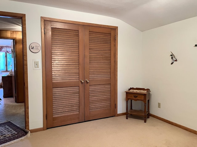 unfurnished bedroom with light carpet, vaulted ceiling, and a closet