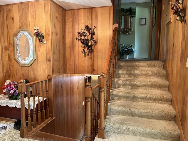 stairway featuring wooden walls