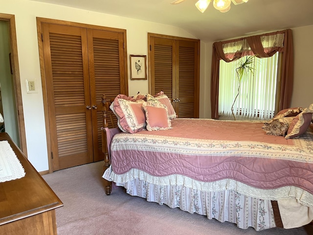 bedroom with ceiling fan, vaulted ceiling, carpet, and multiple closets