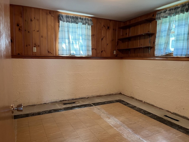 tiled spare room with plenty of natural light and wood walls