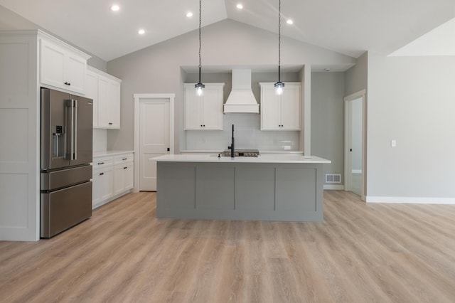 kitchen featuring white cabinetry, high end fridge, custom exhaust hood, and a center island with sink