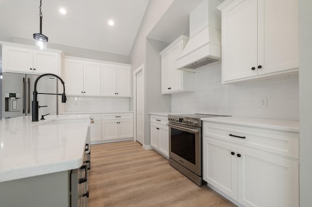 kitchen with appliances with stainless steel finishes, decorative light fixtures, white cabinets, custom exhaust hood, and light wood-type flooring