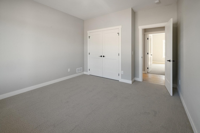 unfurnished bedroom with light carpet and a closet