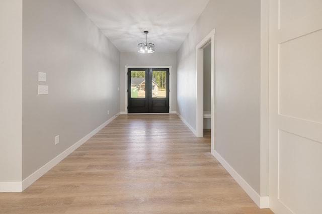 entryway with french doors, a chandelier, and light hardwood / wood-style floors