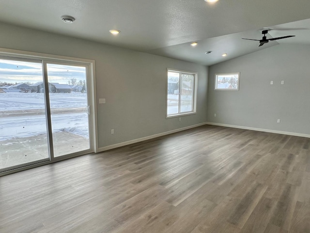 empty room featuring hardwood / wood-style floors, a textured ceiling, vaulted ceiling, and ceiling fan