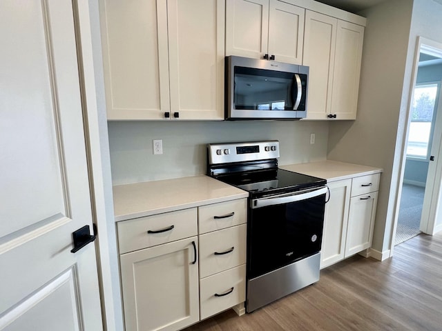 kitchen with light wood-type flooring, white cabinetry, and stainless steel appliances