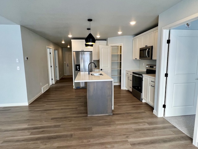 kitchen featuring stainless steel appliances, sink, decorative light fixtures, a center island with sink, and white cabinets