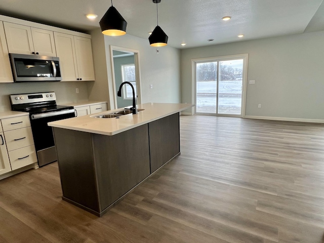 kitchen featuring a center island with sink, sink, decorative light fixtures, white cabinetry, and stainless steel appliances