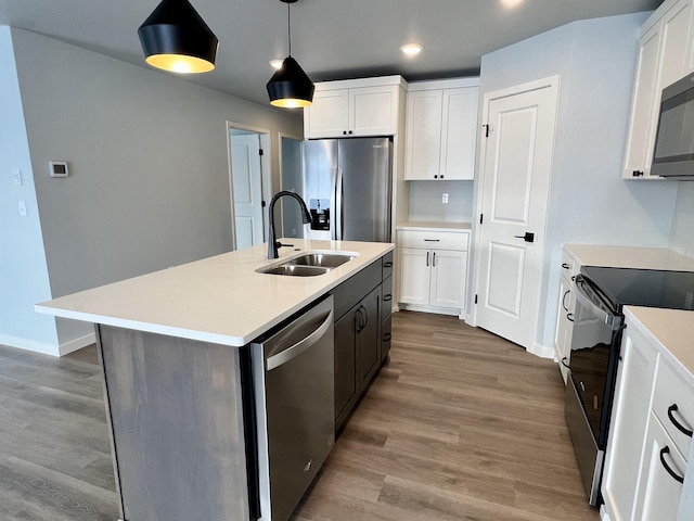 kitchen with sink, hanging light fixtures, stainless steel appliances, hardwood / wood-style floors, and white cabinets