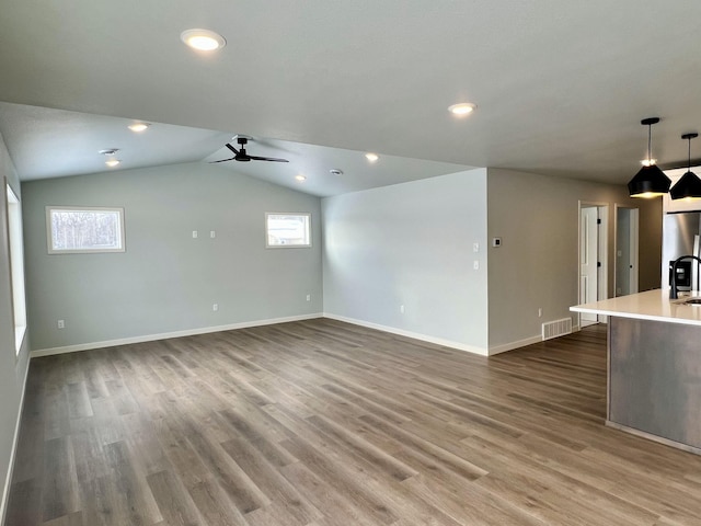 unfurnished living room with ceiling fan, lofted ceiling, and dark wood-type flooring