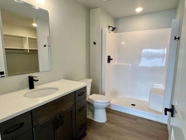 bathroom featuring hardwood / wood-style flooring, vanity, toilet, and walk in shower