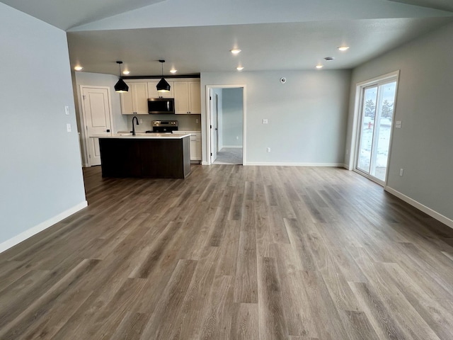 unfurnished living room featuring hardwood / wood-style floors, lofted ceiling, and sink