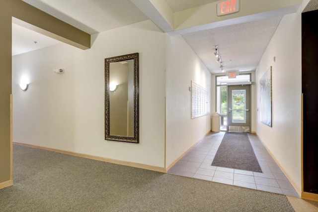 interior space featuring a textured ceiling, rail lighting, light carpet, and french doors