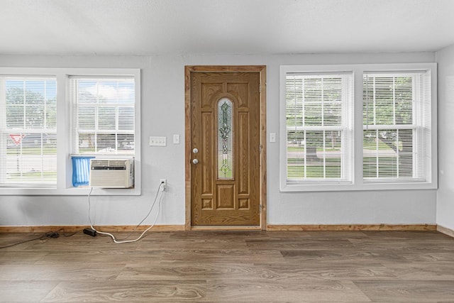 foyer entrance featuring hardwood / wood-style flooring, cooling unit, and plenty of natural light