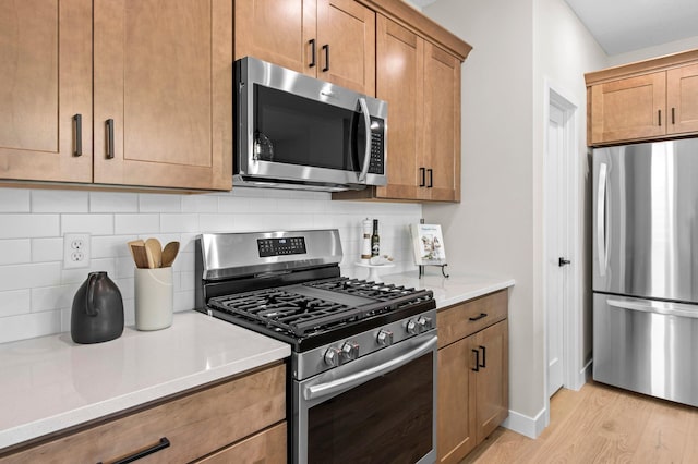 kitchen featuring appliances with stainless steel finishes, decorative backsplash, and light hardwood / wood-style floors