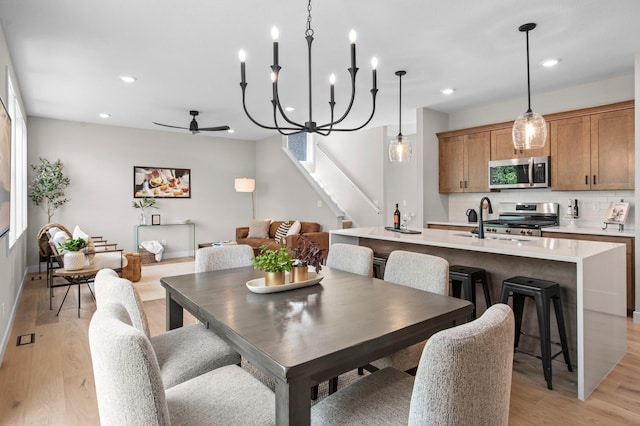 dining room with sink, ceiling fan with notable chandelier, light hardwood / wood-style floors, and a healthy amount of sunlight