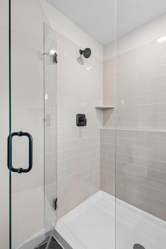 bathroom with a textured ceiling and an enclosed shower