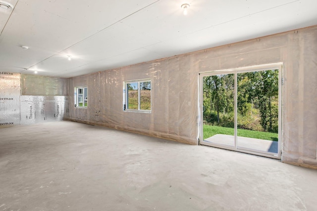 unfurnished living room featuring plenty of natural light and concrete flooring