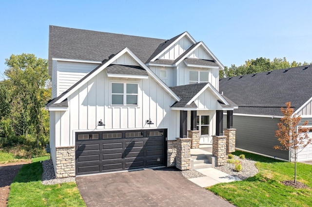 view of front of property featuring stone siding, board and batten siding, driveway, and a shingled roof