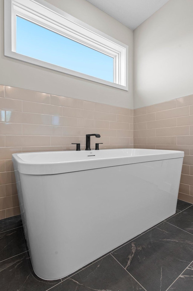 bathroom with tile walls, a healthy amount of sunlight, and a bathing tub