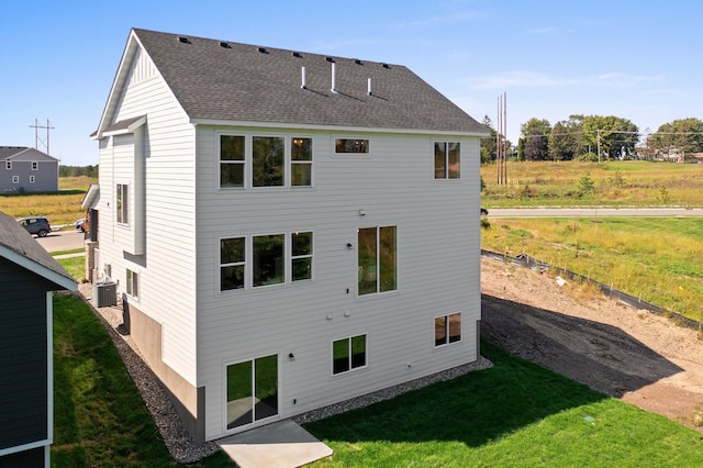 rear view of house with cooling unit and a yard