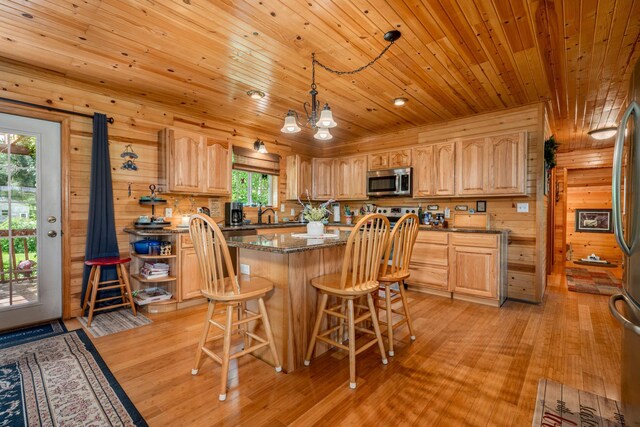 kitchen with wooden walls, light hardwood / wood-style floors, decorative light fixtures, dark stone countertops, and wooden ceiling