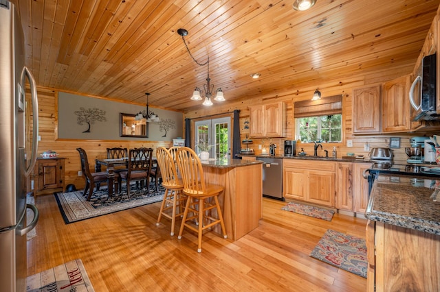 kitchen featuring light hardwood / wood-style flooring, an inviting chandelier, appliances with stainless steel finishes, sink, and a kitchen bar