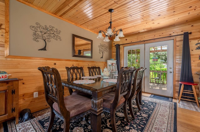 dining room with wooden walls, wood ceiling, hardwood / wood-style flooring, a notable chandelier, and ornamental molding