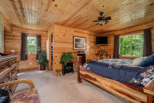 carpeted bedroom with wood walls and wood ceiling