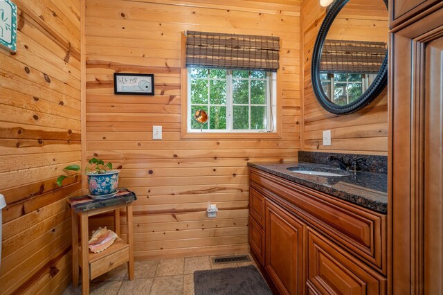 bathroom with wood walls, vanity, and tile patterned flooring