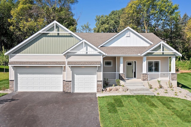 craftsman-style home featuring a shingled roof, a front lawn, a porch, a garage, and stone siding