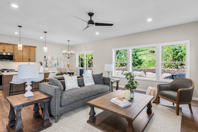 living room featuring ceiling fan with notable chandelier and light hardwood / wood-style flooring