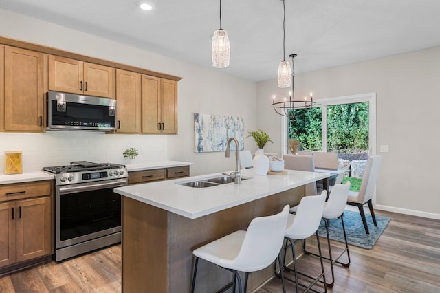 kitchen featuring sink, hardwood / wood-style floors, appliances with stainless steel finishes, and an inviting chandelier