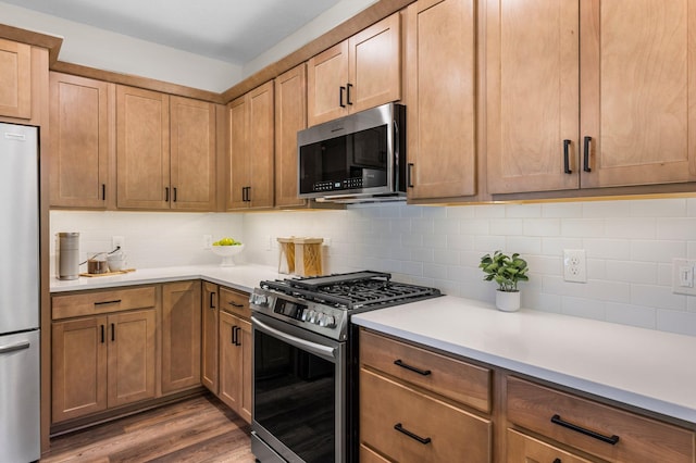 kitchen featuring appliances with stainless steel finishes, hardwood / wood-style flooring, and tasteful backsplash