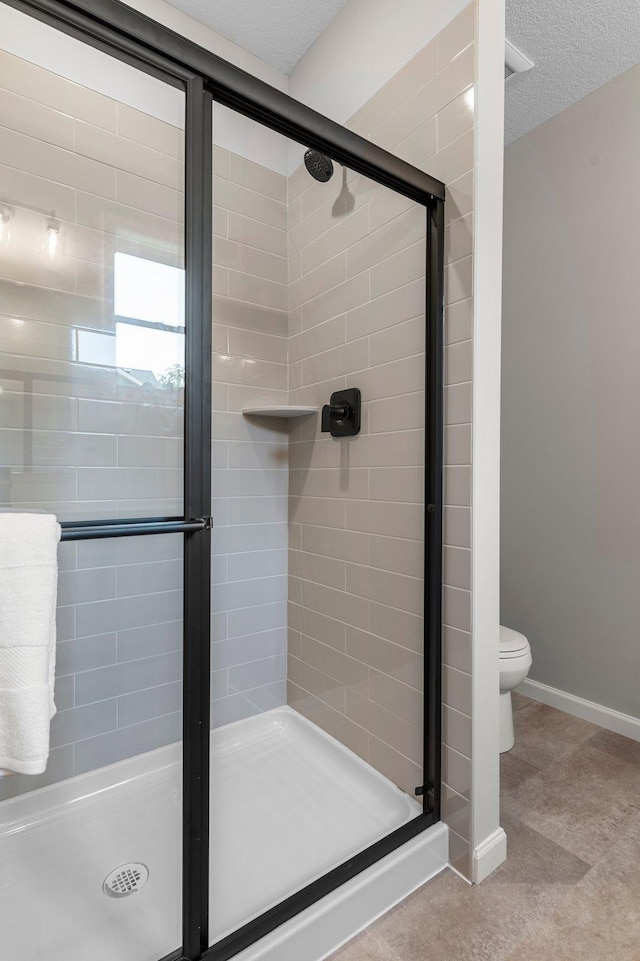 bathroom featuring an enclosed shower, toilet, and a textured ceiling