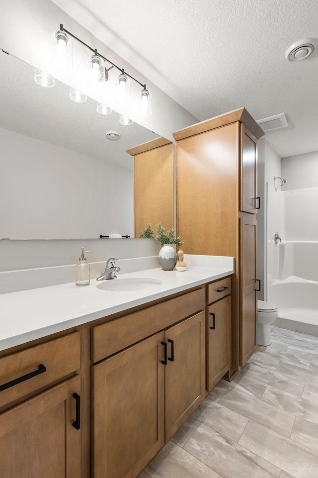 bathroom with walk in shower, toilet, a textured ceiling, and vanity