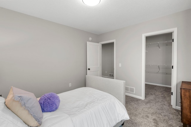 bedroom featuring light colored carpet, a walk in closet, and a closet