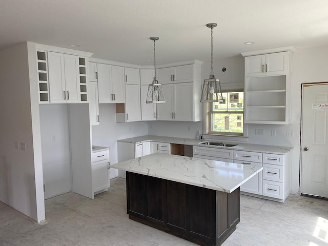 kitchen with a kitchen island, pendant lighting, light stone countertops, and white cabinets