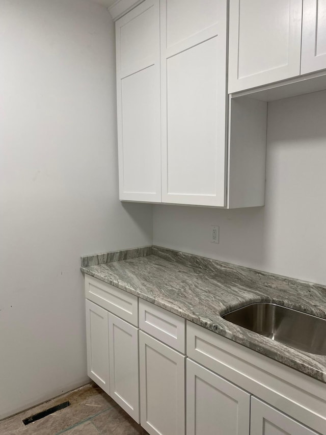 kitchen with tile patterned flooring, white cabinetry, and light stone countertops