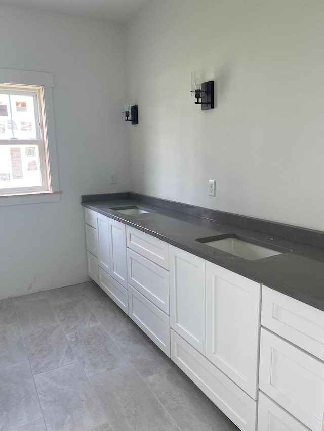 interior space with white cabinetry, dark countertops, and a sink