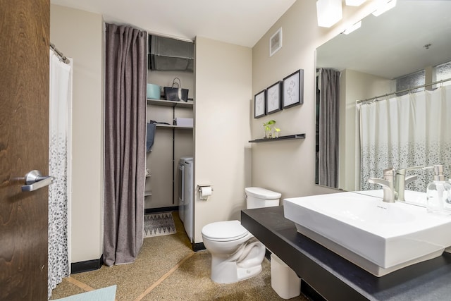 bathroom with washing machine and clothes dryer, toilet, and sink