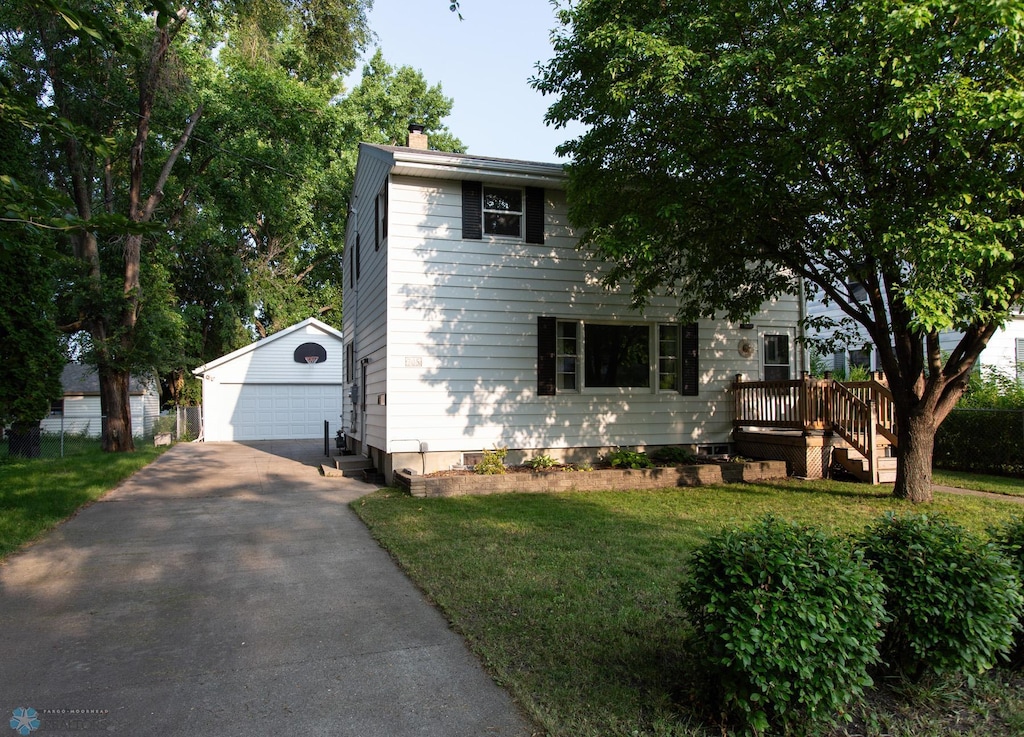 view of front of house with a garage, an outbuilding, and a front lawn