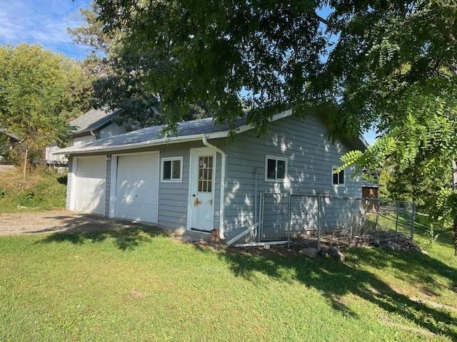 back of property with a lawn and a garage