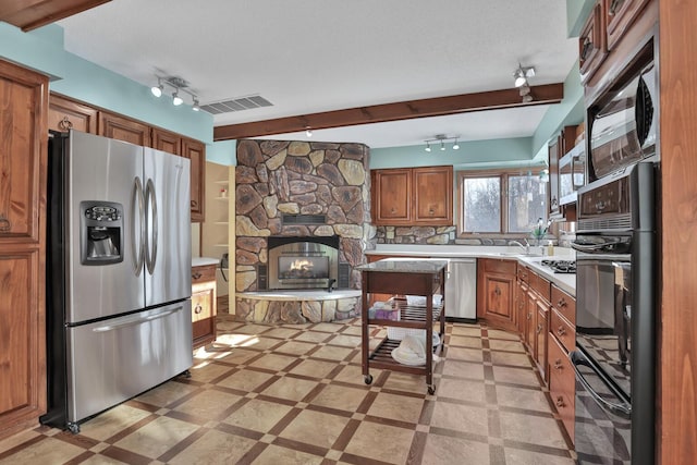 10834 178th Cir NW, Elk River, MN 55330 - kitchen featuring stainless steel appliances, brown cabinetry, light countertops, a fireplace, and track lighting
